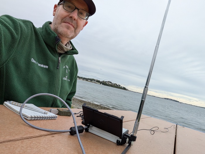 Selfie of Chris Farnham (W1YTQ) operating the KH1 with the harbor behind him