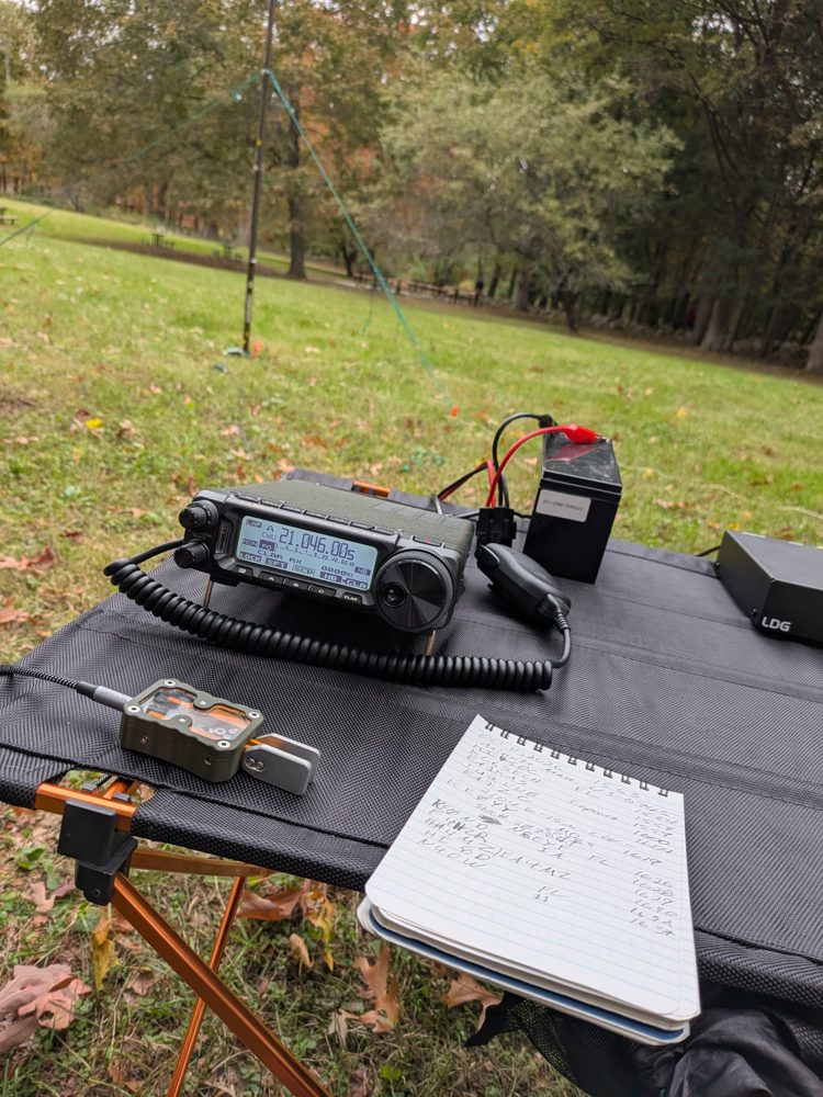 The FT-891 tuned to 21.046 MHz with a paddle key, notebook and the LDG tuner on the table