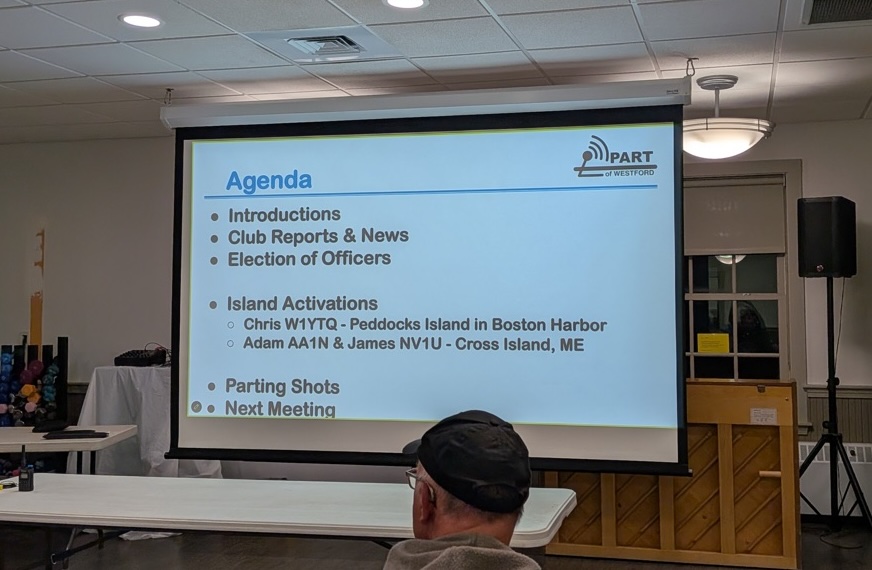 The meeting agenda on the projector screen: Introductions, Club Reports and News, Election of Officers, then Island Activations with Chris W1YTQ on Peddocks Island in Boston Harbor and Adam AA1N and James NV1U on Cross Island, ME